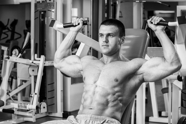 Muscular man working out with weights in gym. Man makes exercises. - Foto, Bild