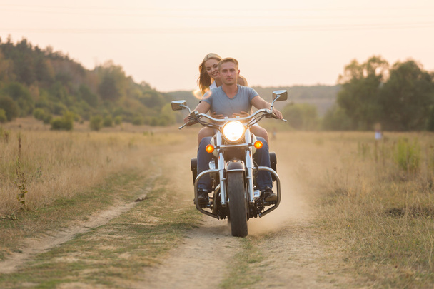 Newlyweds middle of the field on a motorcycle road. Happy couple traveling on a motorcycle. - Fotó, kép