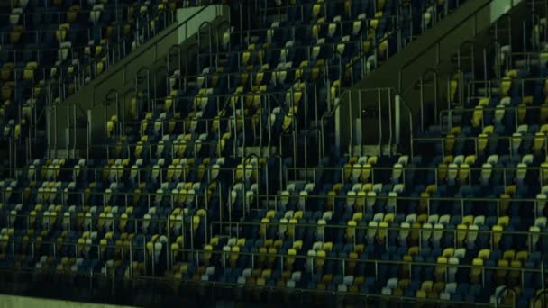 Reihen blauer und gelber Sitze mit Geländern auf einer Tribüne in einer Sportarena. - Filmmaterial, Video