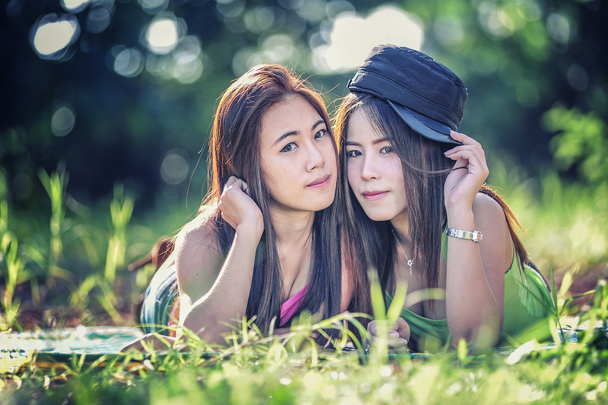 две азиатские девушки, лежащие на траве
 - Фото, изображение