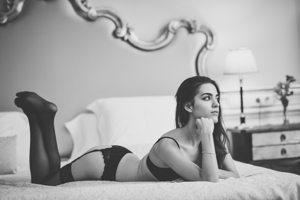 Сексуальна молода жінка в нижній білизні позує на ліжку
 - Фото, зображення