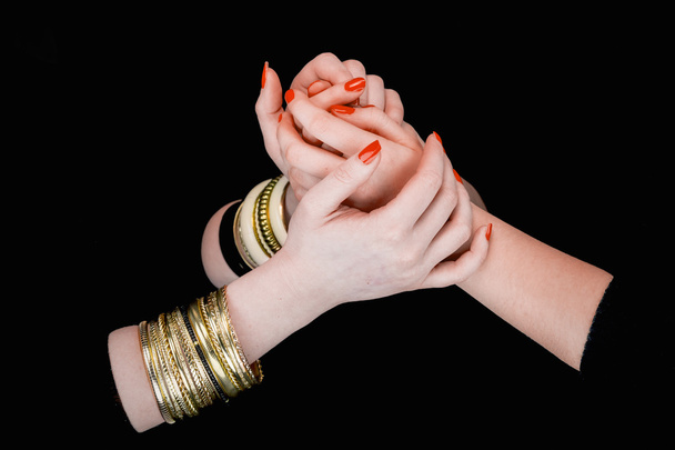 Two women's hands with bracelets holding each other  - Zdjęcie, obraz