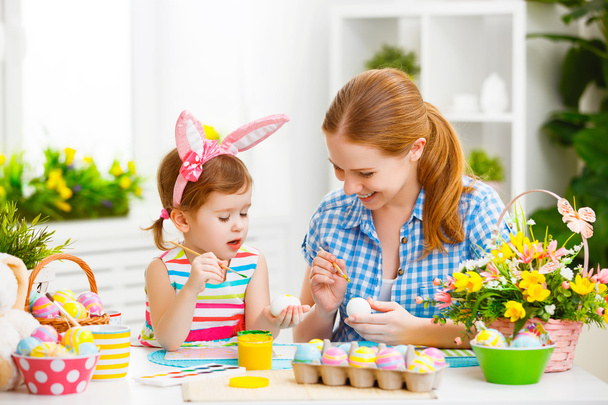 Szczęśliwa rodzina matka i dziecko dziewczynka farby jajka na Wielkanoc - Zdjęcie, obraz