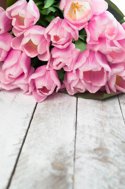 Розовые тюльпаны над потрепанным белым деревянным столом - Фото, изображение