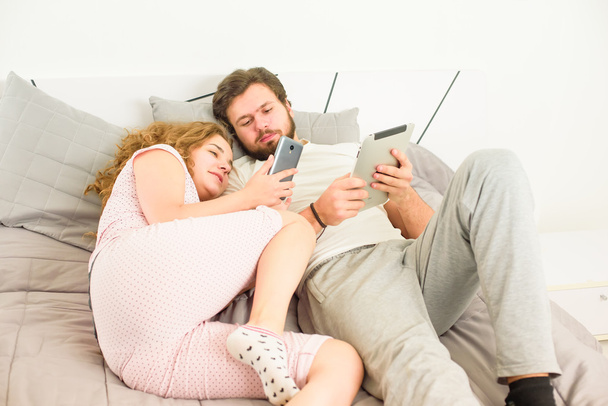 ζευγάρι στο κρεβάτι με tablet και έξυπνο τηλέφωνο - Φωτογραφία, εικόνα