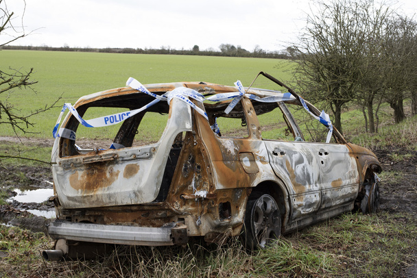Carro queimado com fita de polícia no campo
 - Foto, Imagem