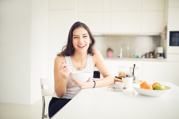 Young smiling woman eating cereal and smiling.Healthy breakfast.Starting your day.Dieting,fitness and wellbeing.Positive energy and emotion.Productivity,happiness,enjoyment concept. - Фото, зображення