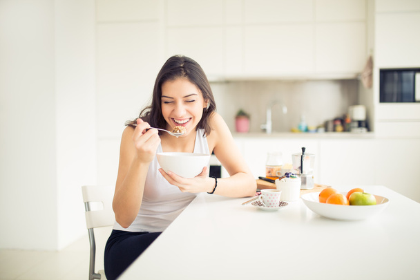 Young smiling woman eating cereal and smiling.Healthy breakfast.Starting your day.Dieting,fitness and wellbeing.Positive energy and emotion.Productivity,happiness,enjoyment concept. - Φωτογραφία, εικόνα