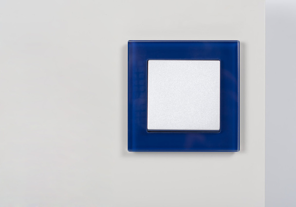 villanykapcsoló kék üveg kerettel a falon - Fotó, kép