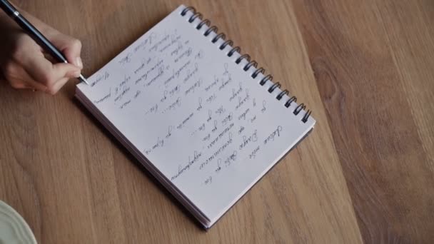 Hands drawing in notebook on bege table - Video, Çekim