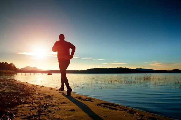 A csodálatos nyári naplementében sport és egészséges életmód tengerpartja mentén futó sportember - Fotó, kép