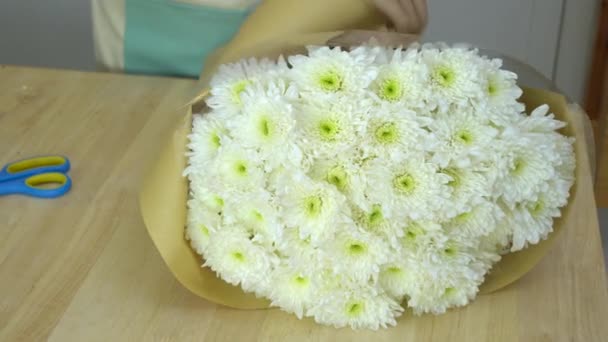 Blumenladen, Blumenstrauß arrangieren, Blumenladen, braunes Geschenkpapier um weißen Mütterstrauß wickeln - Filmmaterial, Video