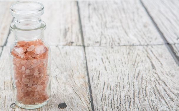 Himalayan rock salt in glass vial over wooden background - Photo, Image