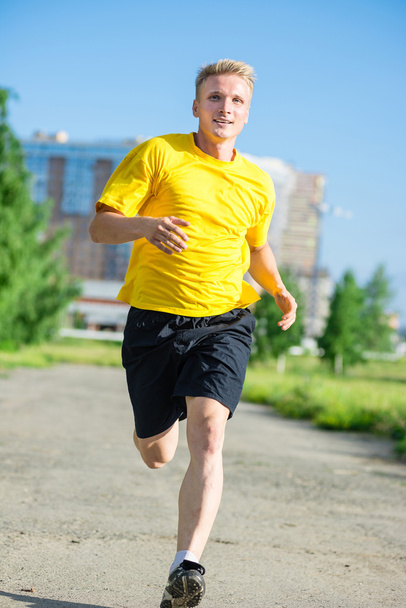 Sporty man jogging in city street park. Outdoor fitness. - Zdjęcie, obraz