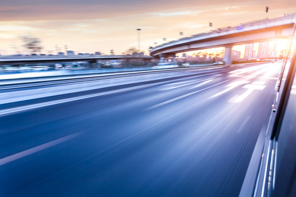 Auto rijden op de snelweg bij zonsondergang, bewegingsvervaging - Foto, afbeelding