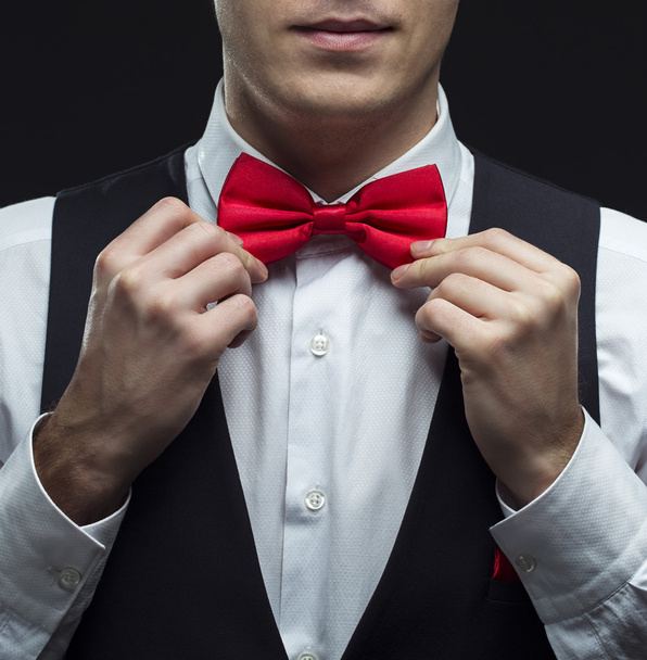 schöner eleganter junger Modemann im schwarzen klassischen Kostümanzug, weißem Hemd und roter Fliege - Foto, Bild