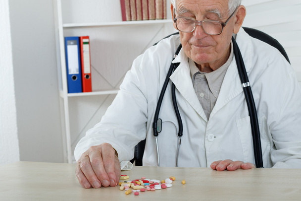 Old doctor with glasses study lot of  pills - Foto, Bild