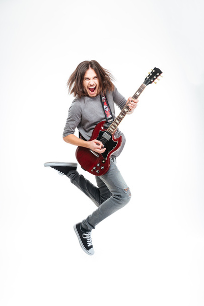 Homme heureux avec des cheveux longs sautant et jouant de la guitare électrique
 - Photo, image