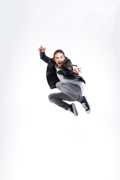 Счастливый красивый молодой человек показывает победный жест и прыжки
 - Фото, изображение