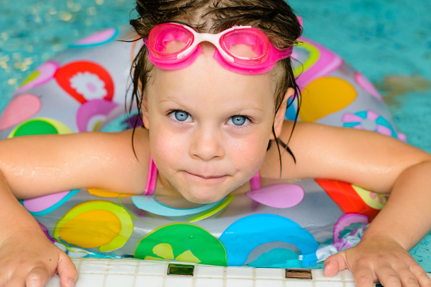 Funny little girl in pink goggles in the swimming pool - Фото, зображення