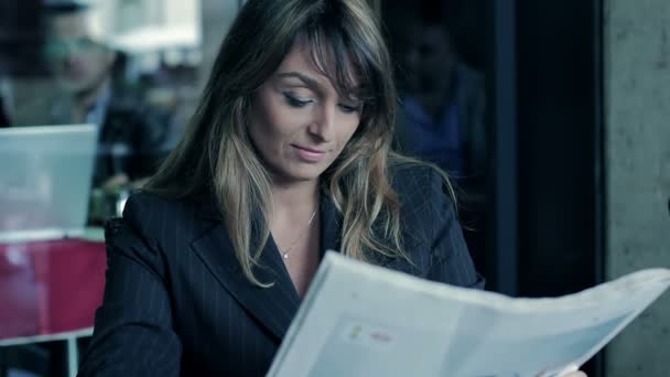 Brunette business woman in cafe reading newspaper - Filmagem, Vídeo