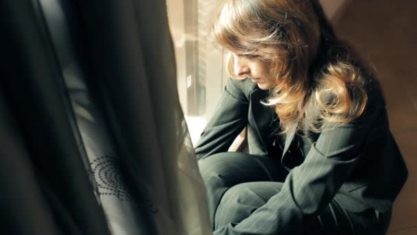 Triste mujer de negocios sentada en el suelo cerca de la ventana
 - Imágenes, Vídeo