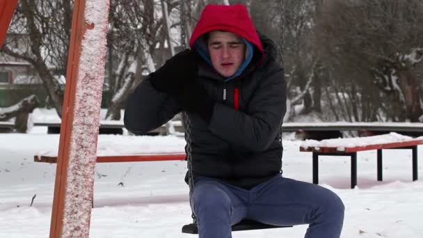 Depressed teenager sitting on swing in winter - Footage, Video