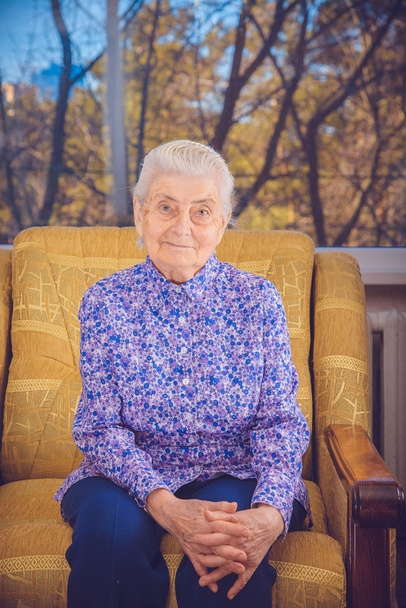 Grandma sitting in a yellow chair - Foto, Imagen