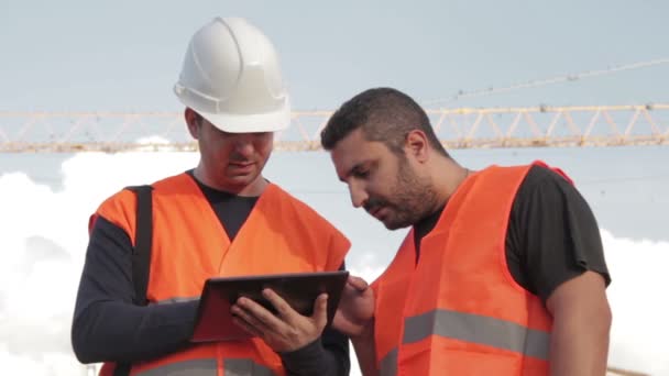 Rakennustyöntekijät, jotka käyttävät sähköistä tablettia paikan päällä
 - Materiaali, video