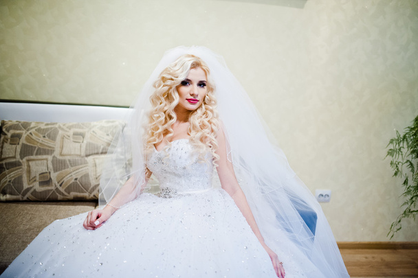 lockige blonde Braut sitzt und posiert auf dem Sofa - Foto, Bild