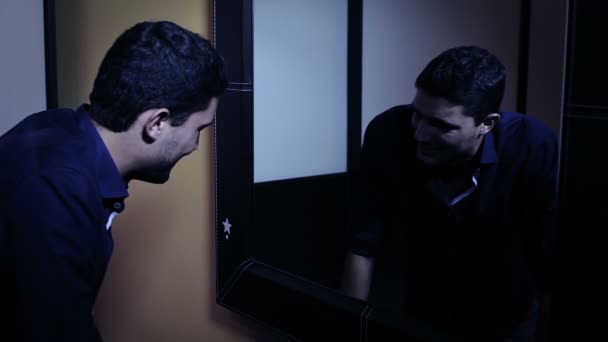Depressed man looking in the mirror at his angry reflection - Кадры, видео