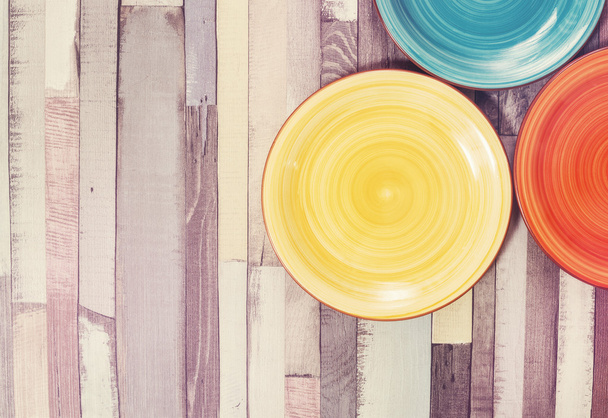 Colored plates on the wooden background - Foto, Imagen