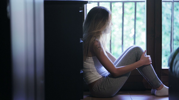fiatal lány ült az ablak közelében - Felvétel, videó