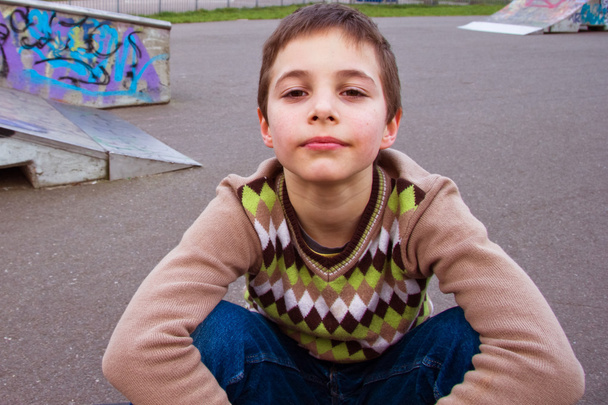 Teen ładny chłopiec siedzi na plac zabaw dla dzieci - Zdjęcie, obraz