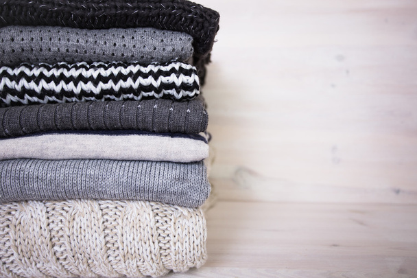 stack of various woolen sweaters on a white wooden background - Photo, Image