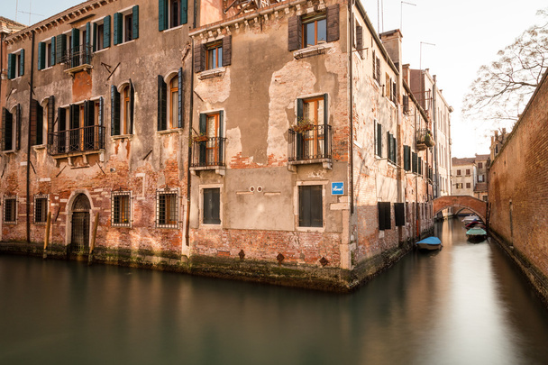 Une vue latérale des vieux bâtiments le long des canaux de Venise pendant la journée. Bateaux peuvent être vus. - Photo, image