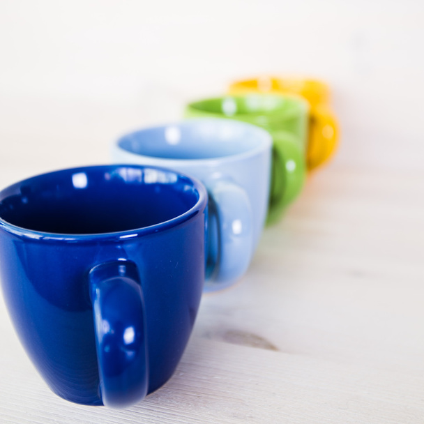 pila de tazas de café de colores sobre un fondo de madera blanca
 - Foto, imagen