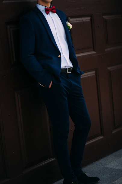  Groom vestindo terno azul e gravata na porta vermelha
.  - Foto, Imagem