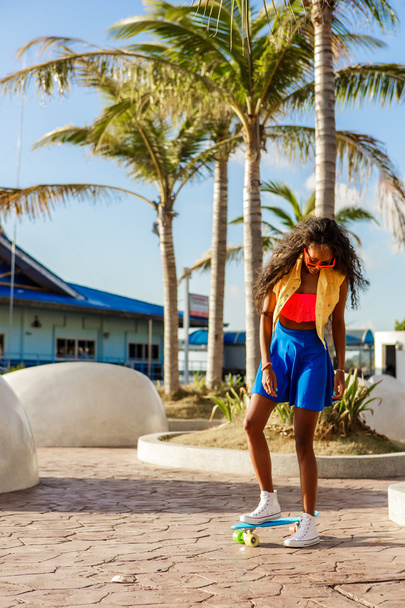 Beautiful teenage black girl in blue skirt stand with her penny  - 写真・画像