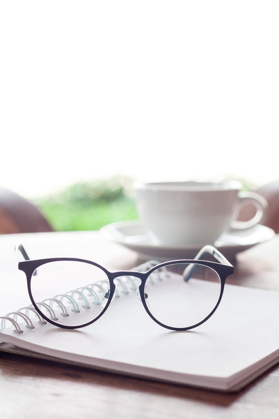 Open blank white notebook and eyeglasses with cup of coffee - 写真・画像