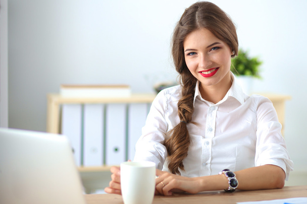 Attractive businesswoman sitting  on desk in the office - Zdjęcie, obraz