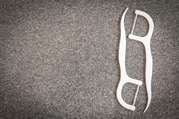 Усні пристрої: біла зубна нитка на тканинному фоні
 - Фото, зображення