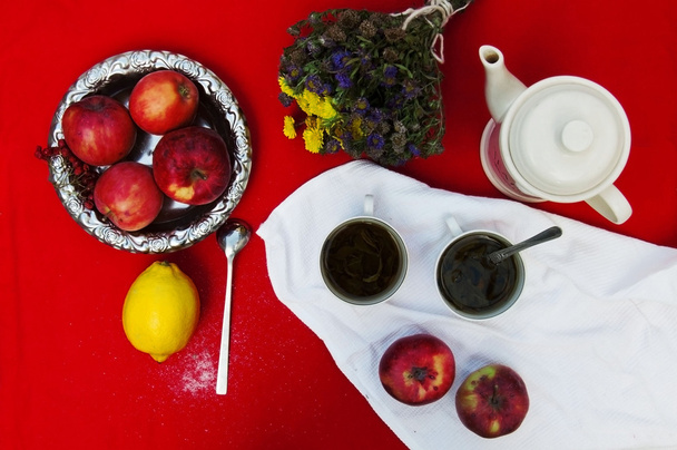 ένα φλιτζάνι τσάι, κίτρινο λεμόνι, ένα κόκκινο φόντο, τρόφιμα και ποτό, - Φωτογραφία, εικόνα