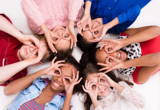 děti, které leží na podlaze hlava k hlavě s brýlemi z prstů - Fotografie, Obrázek