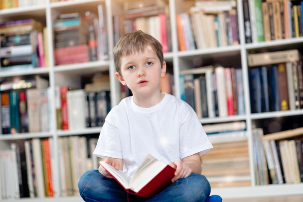 Kisfiú a vörös könyv a könyvtárban - Fotó, kép