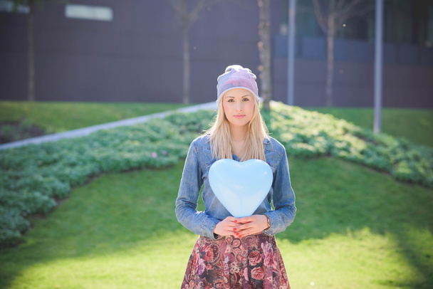 blond meisje met een ballon in vorm van hart - Foto, afbeelding