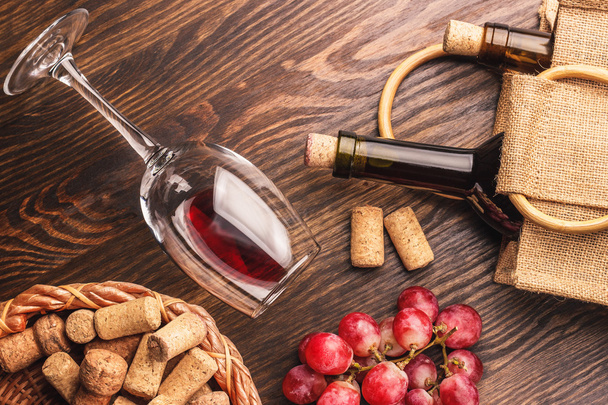 Copa con vino, botellas y racimo de uvas, fondo de madera
 - Foto, imagen