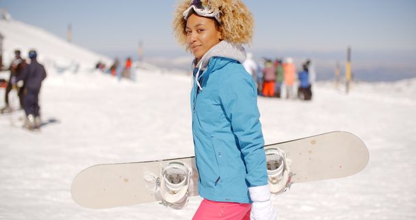 スノーボードを運ぶ若い女性を笑顔 - 写真・画像