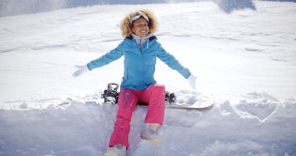 雪の上に座っている若いスノーボーダー - 写真・画像