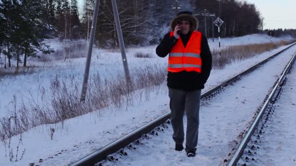 Impiegato ferroviario utilizzando smartphone sulla ferrovia in inverno
 - Filmati, video